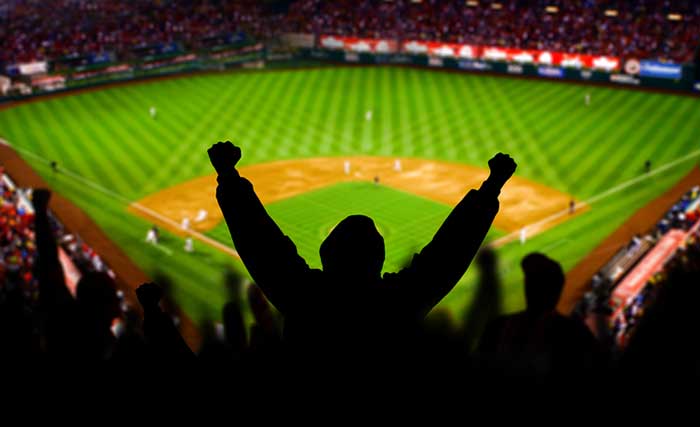 A baseball fan raises his arms in celebration.