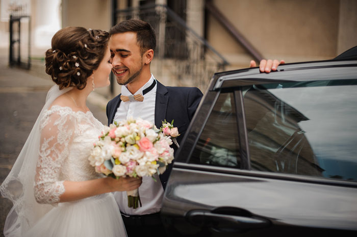 groom opens the door of the wedding car,intending to kiss the bride