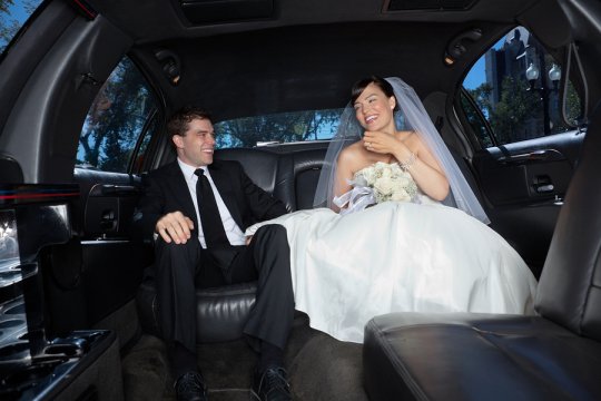 bride and groom smiling in a car