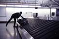 Businessman picking up suitcase on luggage conveyor belt at the airport