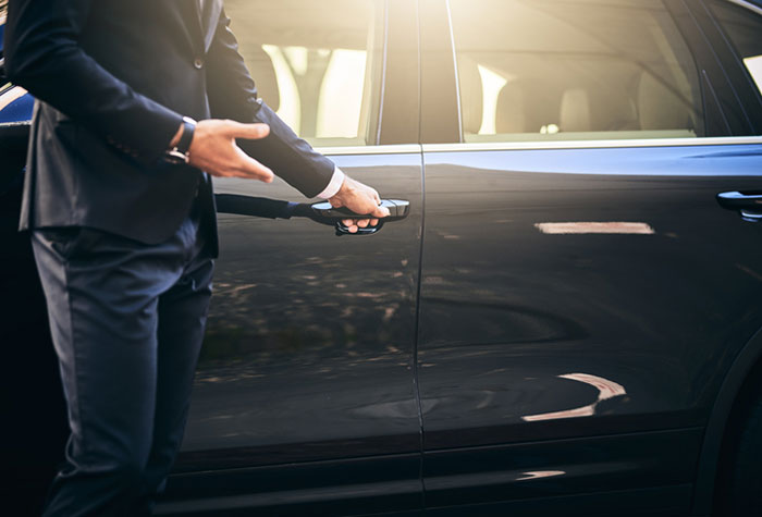 Cropped shot of a well dressed and unrecognizable man opening a car door