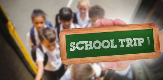 Students holding school trip board