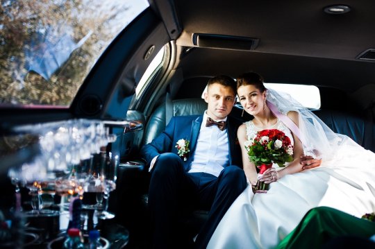 Bride and groom in a car posing for camera