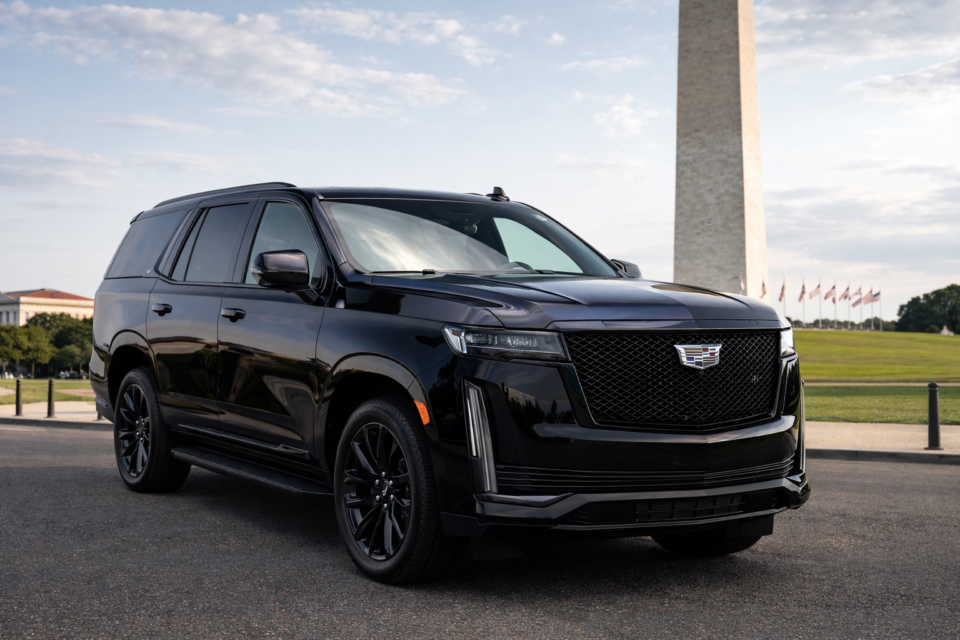 Black Cadillac Escalade parked near the Washington Monument in Washington DC, showcasing luxury full-size SUV design in an iconic urban setting.